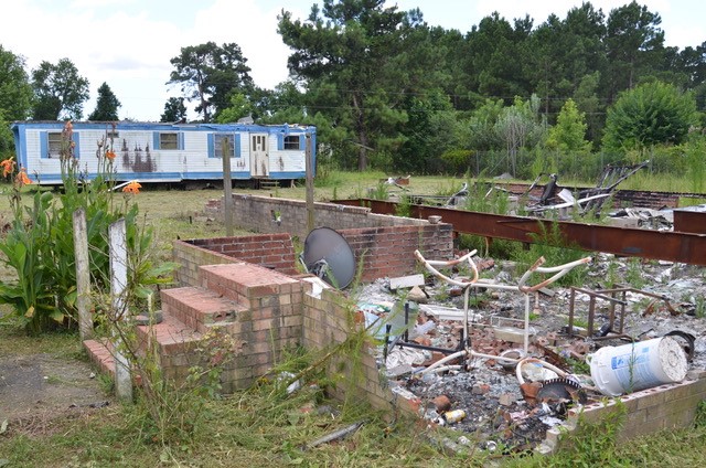 picture of the remains of a burned down home, only the brick steps and foundation remain. charred debris visible within