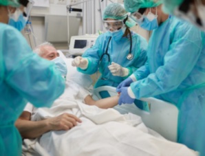 hospital patient surrounded by medical staff in full PPE