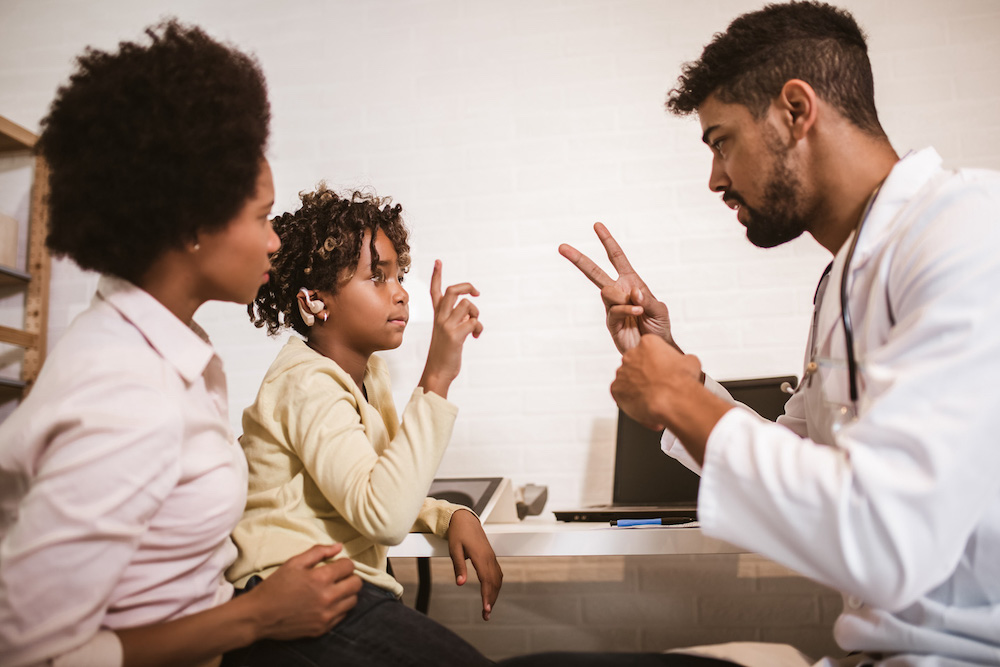 Smiling deaf african american girl with ear implant at doctor's office