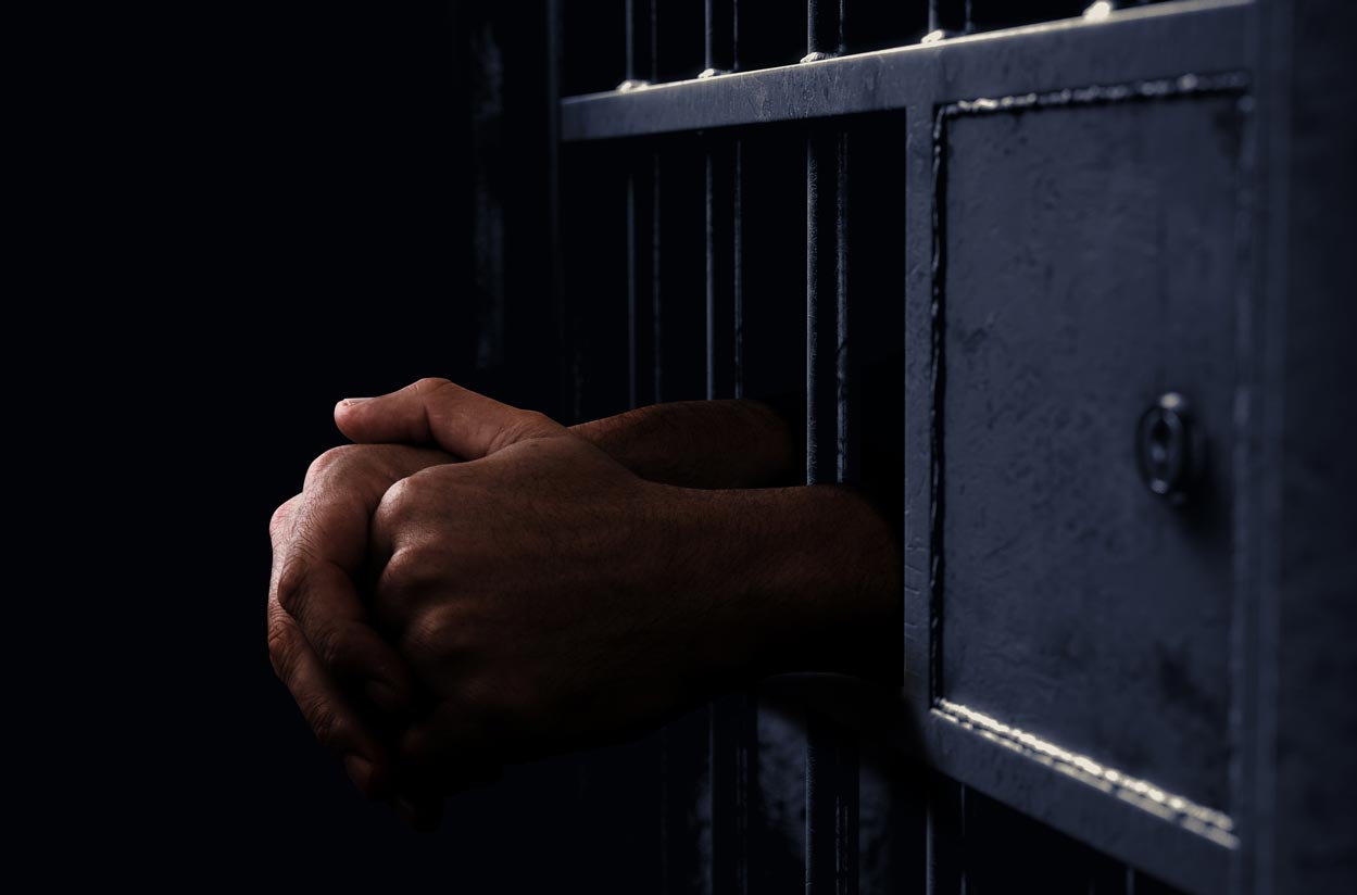 Prison cell with hands showing through grate