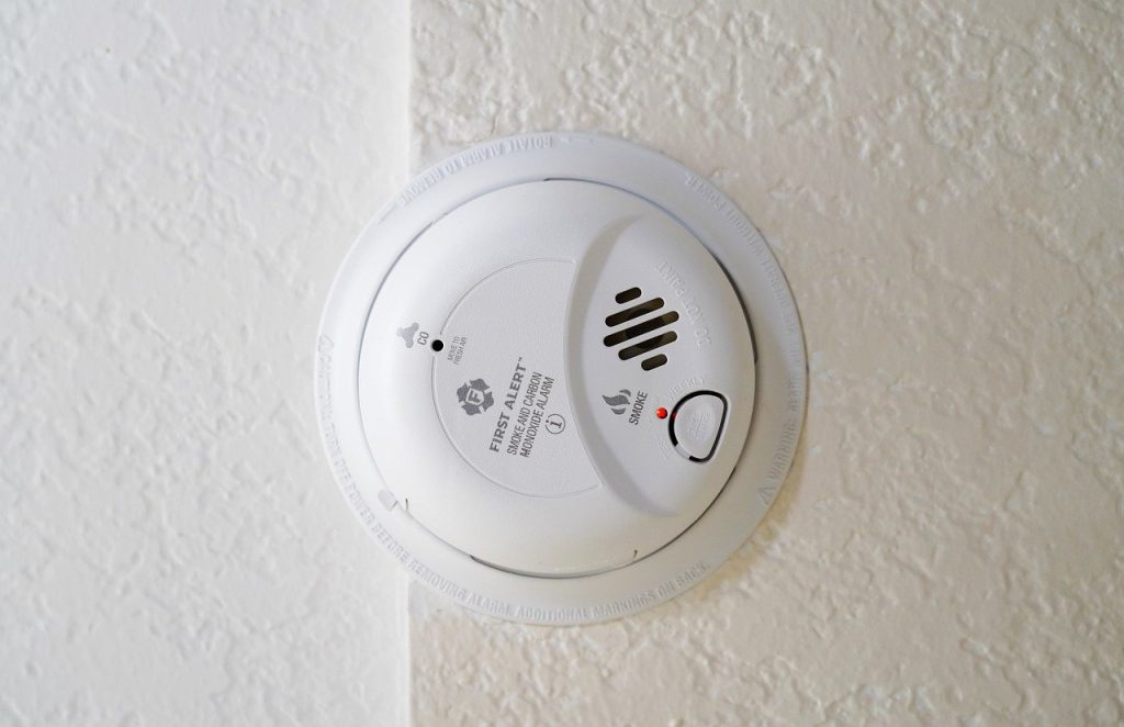 white carbon monoxide detector installed on a white ceiling.