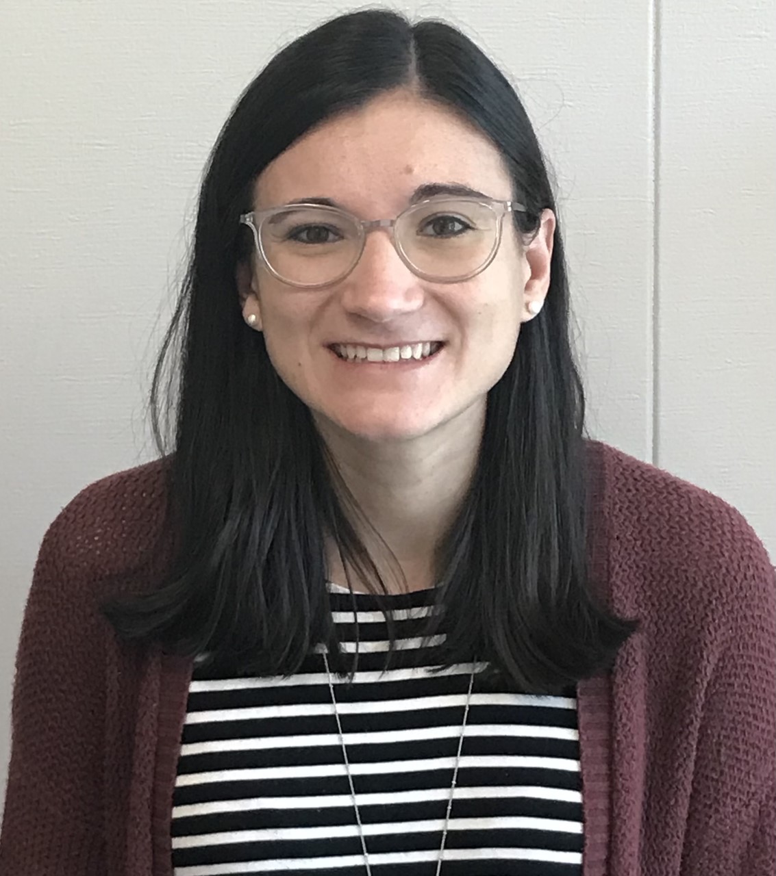 Headshot of Lanie Summerlin, a white female with mid length black hair wearing clear glasses, a black and white striped shirt, and a dark purple cardigan