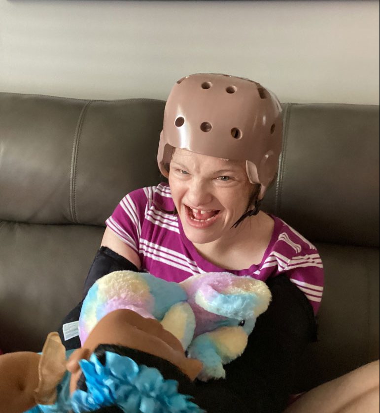 A picture of Samantha wearing a helmet and smiling while sitting on a couch
