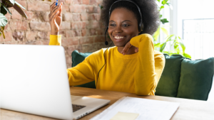 Black woman wearing a yellow shirt at her laptop