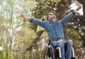 A man in a wheelchair with his hands in the air is looking up at eh size