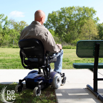 Wheelchair user from back outside near a park bench