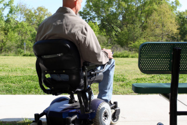 Wheelchair user from back outside near a park bench