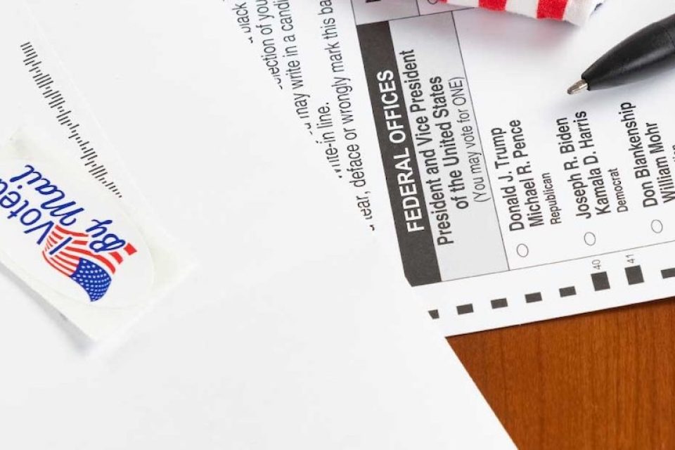 Paper absentee ballot from the 2020 General election laying on a table, with an I voted by mail sticker above
