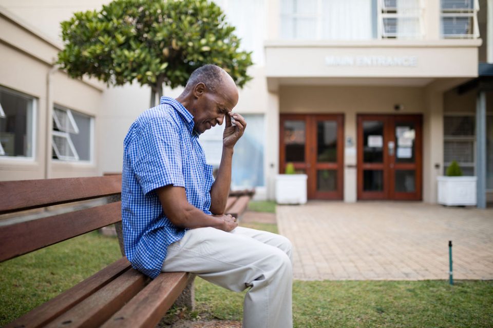 Black man sits in front of community building