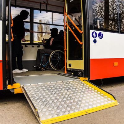 Two men talk on a bus with a wheelchair ramp extended