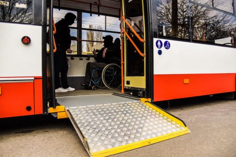 Two men talk on a bus with a wheelchair ramp extended