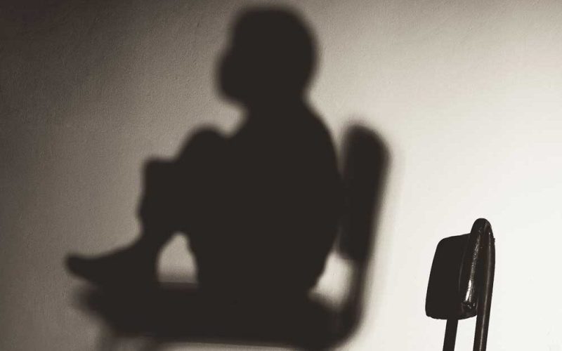 Shadow of kind in chair on wall in front of an empty chair