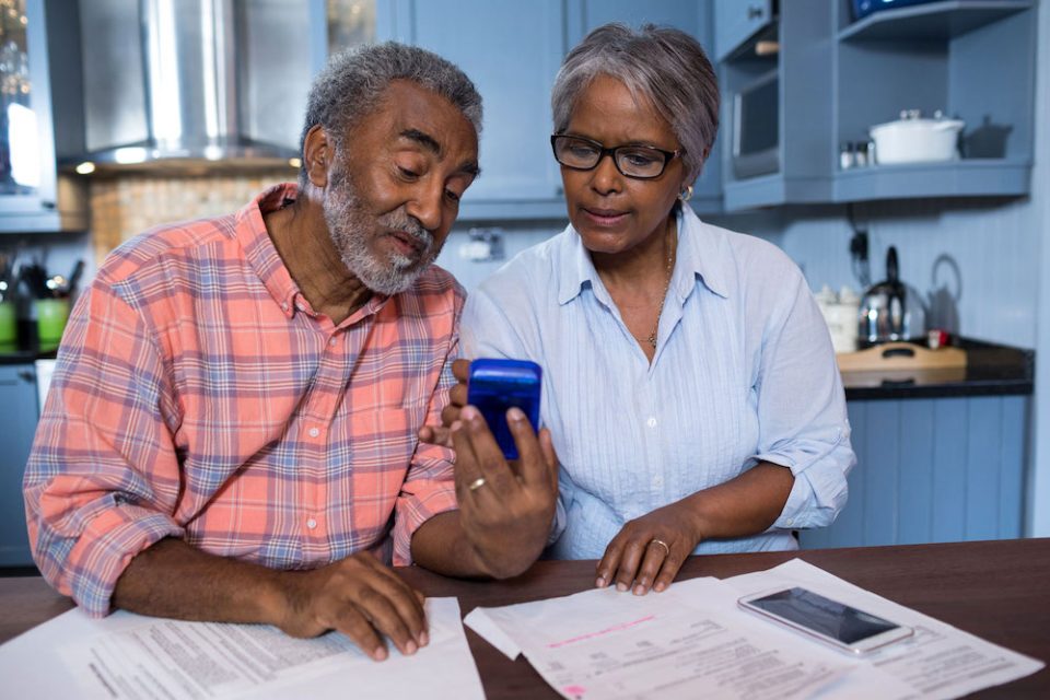 Black couple use smartphone at kitchen table