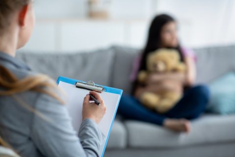 Teenage depression. Psychologist working with teen girl at office, talking to her patient, taking notes, selective focus Teenage depression. Psychologist working with teen girl at office, talking to her patient, taking notes, selective focus