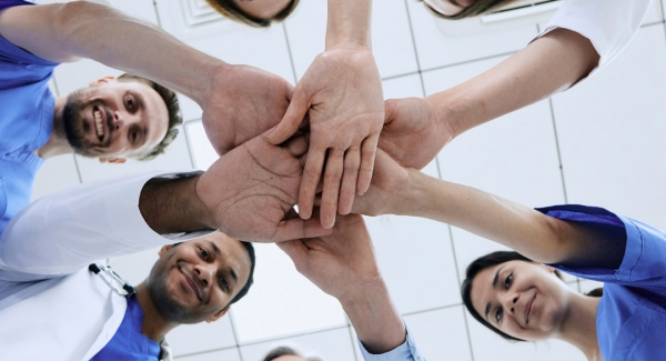 Six individuals putting their hands together