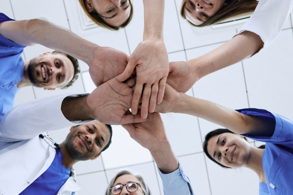 Six individuals putting their hands together