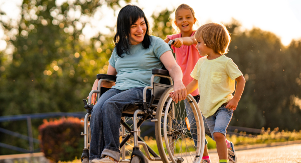 A woman in a wheelchair traveling down a a path with two children