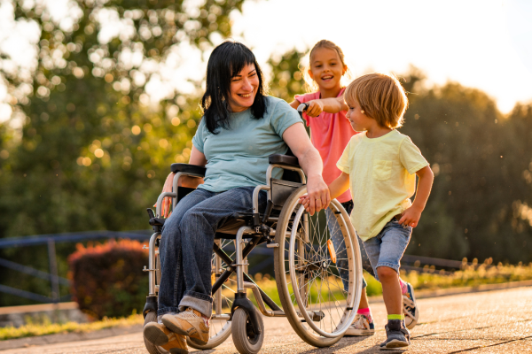 A woman in a wheelchair traveling down a a path with two children