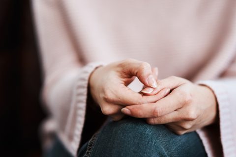 Cropped shot of a woman sitting on a sofa and feeling anxiouCropped shot of a woman sitting on a sofa and feeling anxious, indicated by her hands, which are contorted to indicate worry,