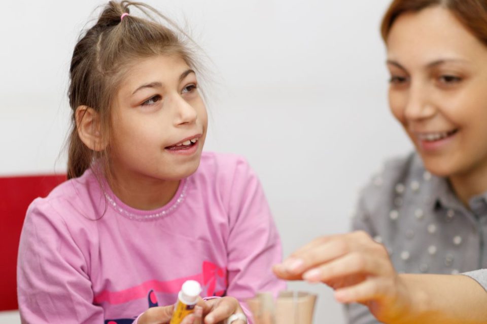 A young girl with disabilities works on a craft project