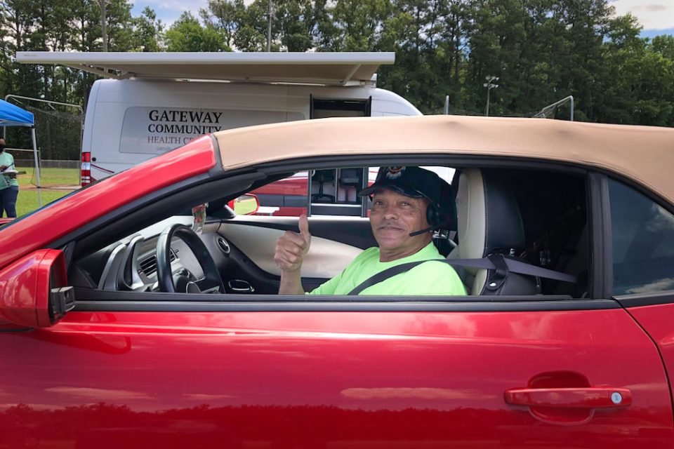 Man in red car gives thumbs up at vaccination drive in gates county