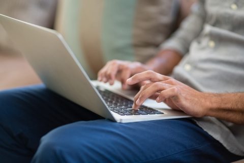 Man with blue jeans typing on a laptop.jpg