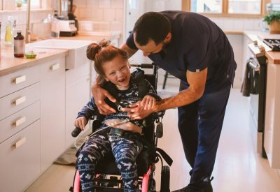 Dad helps young daughter with wheelchair in kitchen