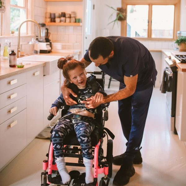 Dad helps young daughter with wheelchair in kitchen