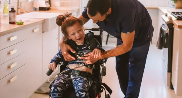 Dad helps young daughter with wheelchair in kitchen