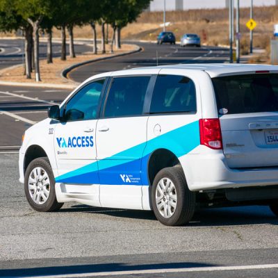 White and blue paratransit van makes a left turn
