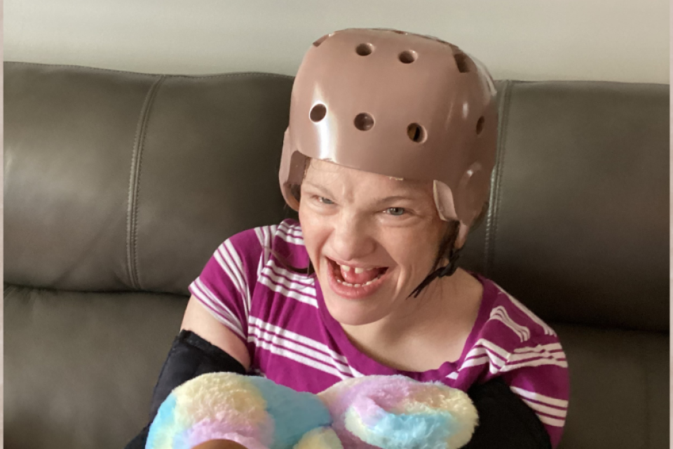 Samantha R on the couch with a protective helmet