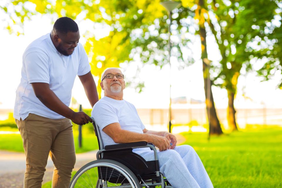 Professional nurse providing special assistance in-home walking outdoors with a patient.