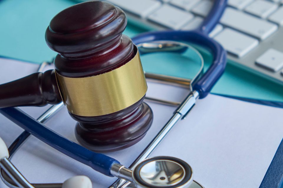 A gavel and stethoscope on top of a computer keyboard