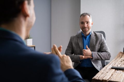 Two men communicate using ASL at a meeting