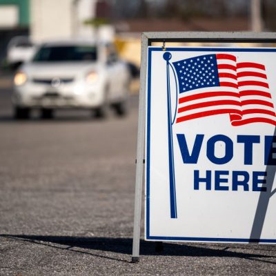 Vote here sign with car in background