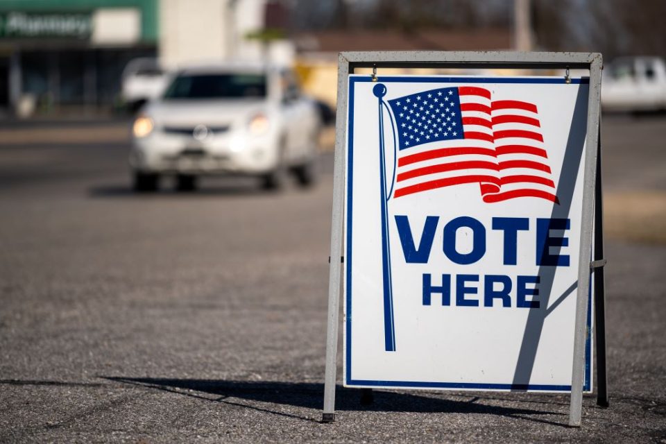 Vote here sign with car in background