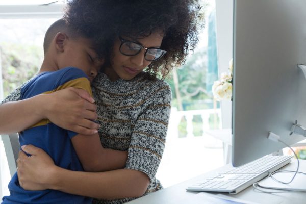 Woman holds son in front of computer