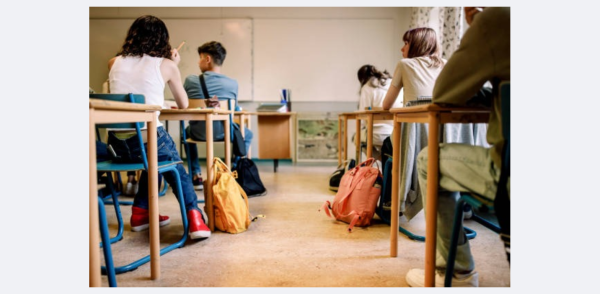 a group of 5 students in a classroom sitting at desks facing away from the camera