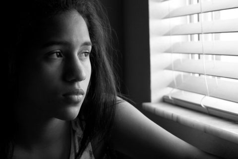Profile of sad latina girl looking out the window pensively