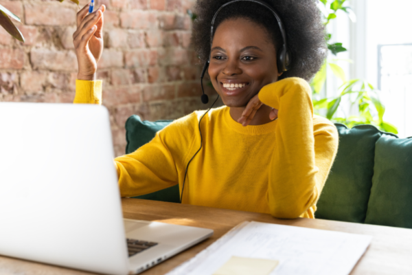 Black woman wearing a yellow shirt at her laptop