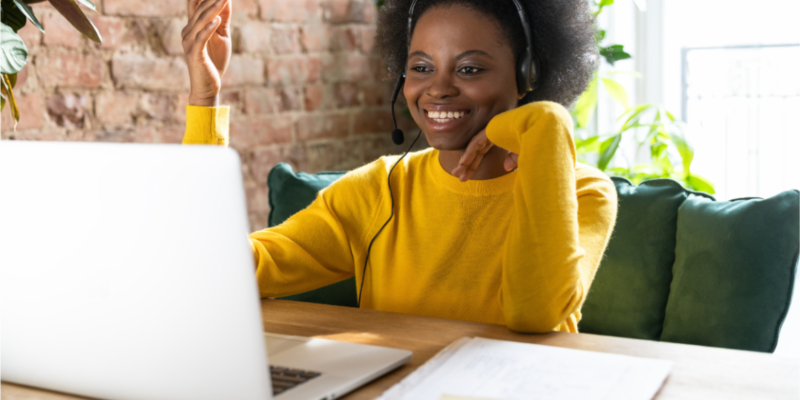 Black woman wearing a yellow shirt at her laptop