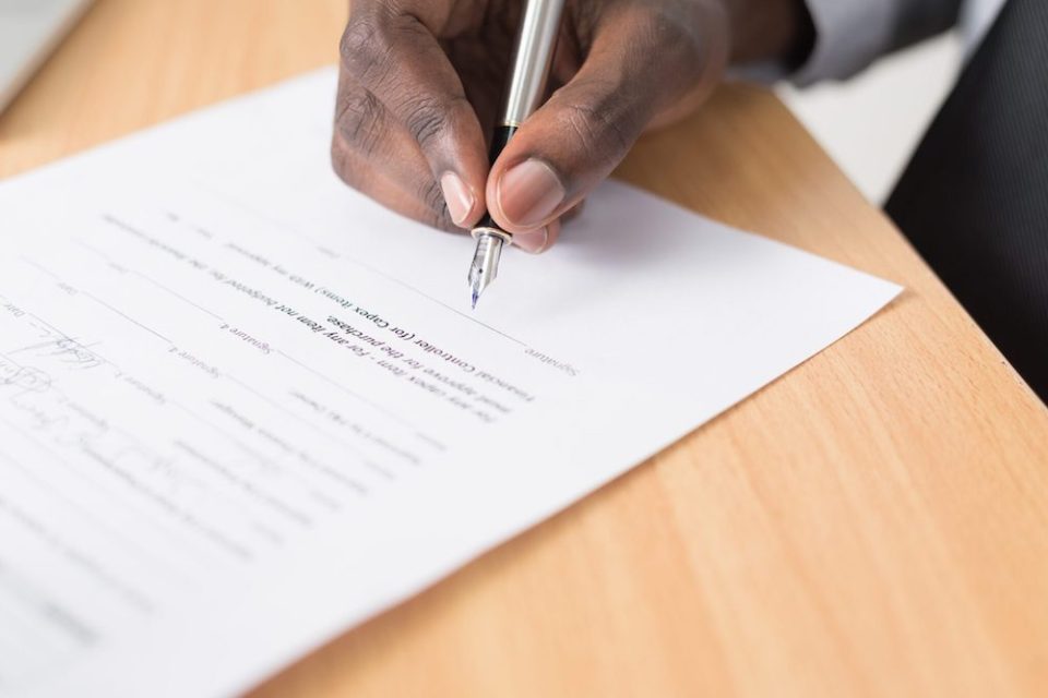 hand of a black man signing a letter