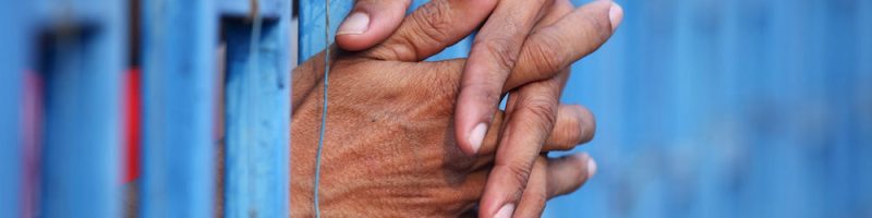 Prisoner's hands sticking through prison bars