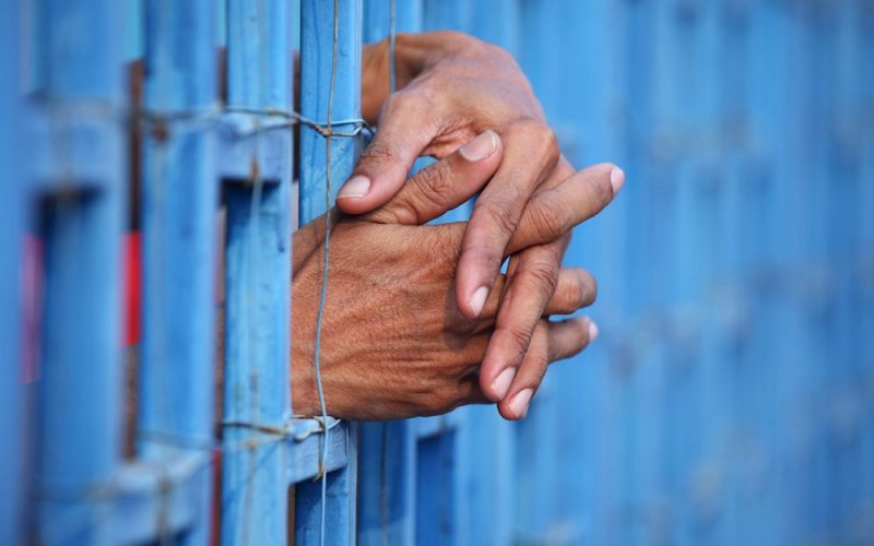 Prisoner's hands sticking through prison bars