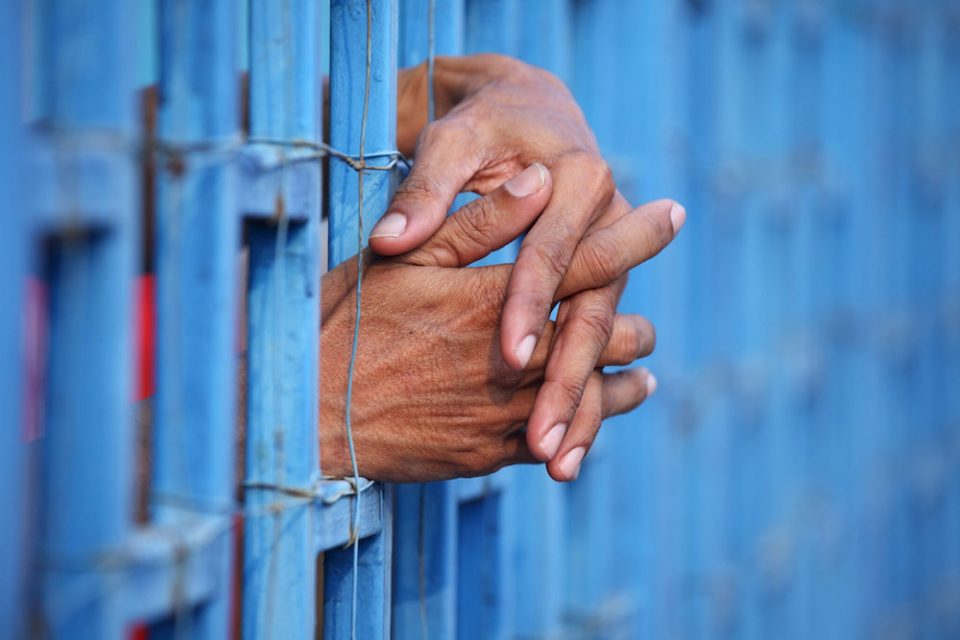 Prisoner's hands sticking through prison bars