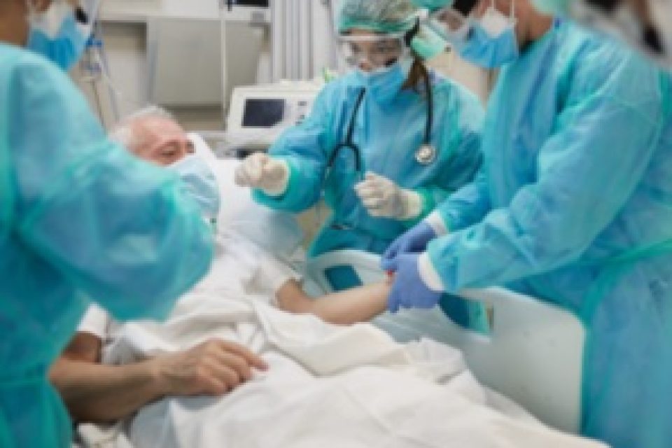hospital patient surrounded by medical staff in full PPE