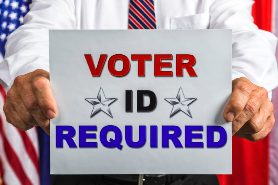 a man holding a sign that reads voter id required
