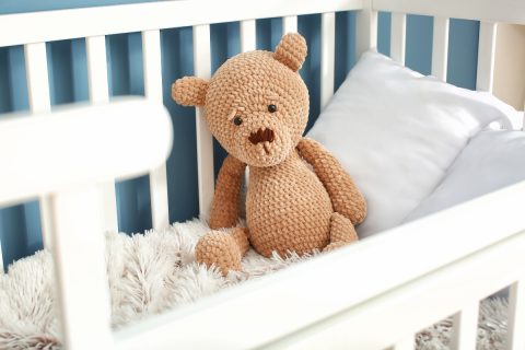 sad teddy bear alone in a child's crib